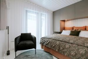 a bedroom with a large bed and a chair at Cliff House Joelahtme Golf Villa with Sauna in Manniva