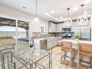 a kitchen with white cabinets and a glass table at Heart of Nampa-Hot Tub-Fenced Yard-Full Kitchen in Nampa