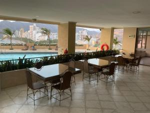 a dining room with tables and chairs and a pool at Rodadero Excelente Apartamento in Puerto de Gaira
