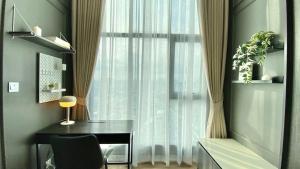 een kamer met een bureau en een raam met gordijnen bij Modiz Modiza Sukhumvit R4 in Bangkok