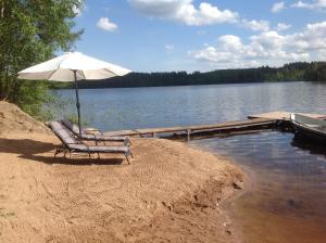a chair with an umbrella sitting on the shore of a lake at Tilhi 1 Cottage in Piojärvi