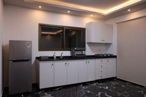 a kitchen with white cabinets and a refrigerator at Sky High Guesthouse in Gharīfah