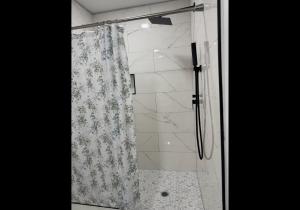 a shower with a glass door with a floral shower curtain at Spacious in Downtown McAllen in McAllen +13 photos