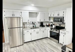 a kitchen with white cabinets and a stainless steel refrigerator at Spacious in Downtown McAllen in McAllen