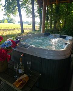 un bain à remous avec une table et des verres de vin dans l'établissement Pipowagen Bijzonder Buitenaf met jacuzzi en sauna, à Vragender