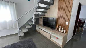 a living room with a staircase with a tv and a stair case at Cantinho aconchego gc in Ubatuba
