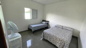 a room with a bedroom with a bed and a fan at Cantinho aconchego gc in Ubatuba
