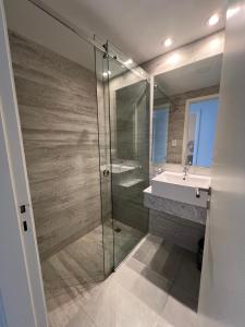 a bathroom with a glass shower and a sink at Departamento de lujo frente al mar con vista panorámica, pileta y cochera privada in Monte Hermoso