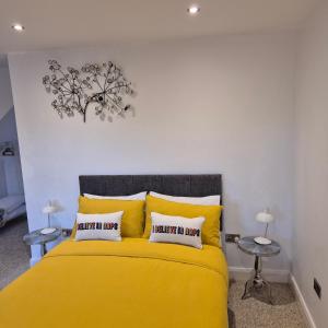 a bedroom with a yellow bed with two tables at Sally's at Number 73 with Private Hot Tub & Sauna in Coleraine