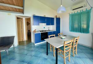 a kitchen with blue cabinets and a table and chairs at Casa Trama in Pisciotta +12 photos