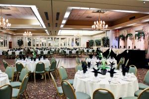 un salón de banquetes con mesas blancas y sillas verdes en University Square Hotel en Fresno