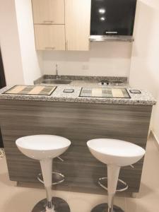 a kitchen with two white stools in front of a counter at Lofts Mediterraneo in Barranquilla