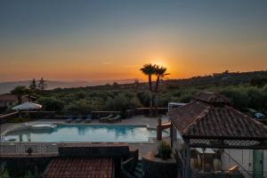 a swimming pool with a sunset in the background at Terre Villa Katia in Santa Maria di Licodia