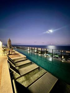 a swimming pool with a view of the ocean at night at UNU 602 Itapuã: piscina, academia, praia e+ in Salvador