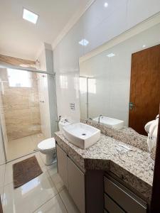 a bathroom with a sink and a toilet and a mirror at Residencial Algarve in Patos de Minas +19 photos