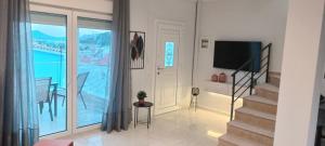 a living room with a television and a balcony at Theo Luxury Apartment in Nea Peramos