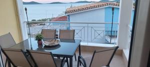 a table and chairs on a balcony with a view of the water at Theo Luxury Apartment in Nea Peramos