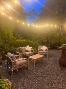 a patio with two chairs and a table and lights at Sparrows Nest Holiday Cottage in Amroth