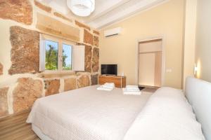 a bedroom with a stone wall with a bed and a tv at Sacuba Resort & Botanic Golf Club in Olbia