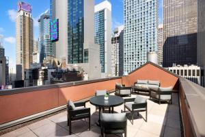 een balkon met een tafel en stoelen en een skyline van de stad bij The Muse New York in New York