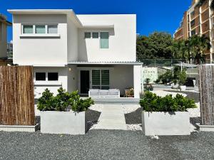 a white house with two potted plants in front of it at Condado Laguna Villa 1 - Spa - 6 Bd 3Ba Generator in San Juan