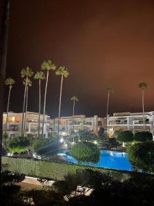a large pool with palm trees in front of a building at Résidence calme et luxueuse in Dar Bouazza
