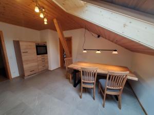 a dining room with a wooden table and two chairs at Biohof Dimper - KuhHorn in Saulgrub