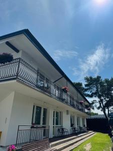 a white house with a balcony with tables and chairs at Pokoje u Alicji in Władysławowo