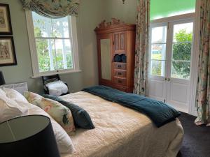 a bedroom with a bed and a dresser and windows at Villa Walton in Matamata +77 photos