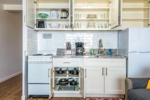 a kitchen with white cabinets and white appliances at Renovated Condo Near Waikiki Beach in Honolulu