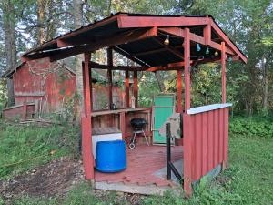 a wooden shelter with a grill in a field at Pet Friendly Retreat - Sleeps 8 with Sauna in Koivisto