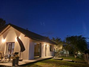 a white house with a table and chairs at night at W Małym Sadzie in Dobra