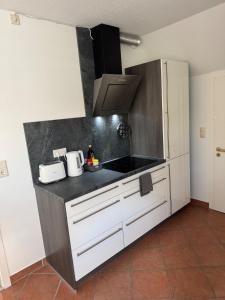 a kitchen with white cabinets and a black counter top at Schöne Ferienwohnung am Waldrand in Detmold