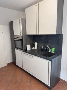 a kitchen with white cabinets and a sink at Schöne Ferienwohnung am Waldrand in Detmold +13 photos