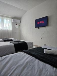 a hotel room with two beds and a tv on the wall at Apartments Una Roots in Orašac