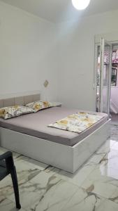 a white bed in a white room with a bed frame at NEAR Guest-house in Durrës