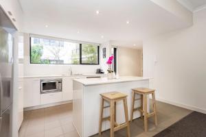 a kitchen with white walls and a counter and stools at Subiaco Rooftop on Sheen in Perth