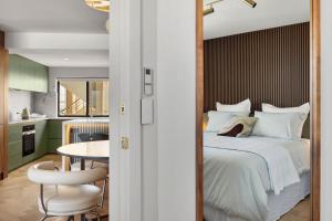 a bedroom with a bed and a table and a kitchen at Cottesloe Neue Blue Apartment in Perth