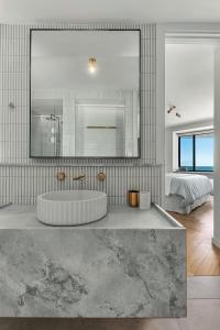 a bathroom with a tub and a large mirror at Cottesloe Neue Blue Apartment in Perth