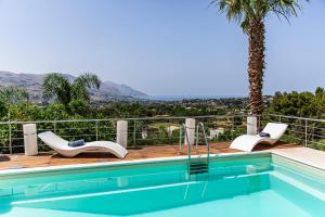 a pool with two chairs and a palm tree at Villa Luna Scopello in Castellammare del Golfo