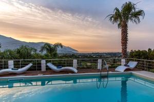 a swimming pool with chairs and a palm tree at Villa Luna Scopello in Castellammare del Golfo