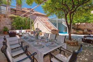 a table and chairs in a yard with a house at Villa Hvar Royale - 5 Bedroom Central Villa - Indoor Pool - Beautiful Heritage Villa in Hvar