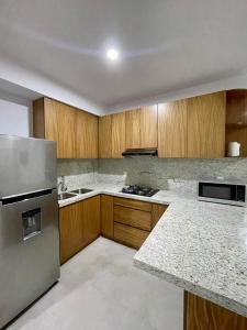 a kitchen with wooden cabinets and a stainless steel refrigerator at Fantástico Depa en BLUU con Playa Artificial ! in Mazatlán