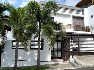 a white house with palm trees in front of it at Casahermosa in Santo Domingo