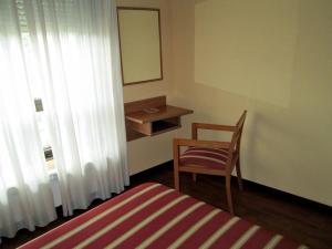 1 dormitorio con cama, silla y espejo en Pensión Teyma, en Ponteceso
