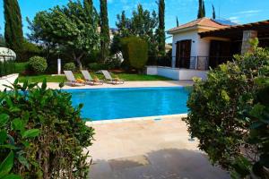 une piscine avec des chaises longues et une maison dans l'établissement Aphrodite Hills Superior Villas Superior Villa 0066 Air Conditioning, à Paphos