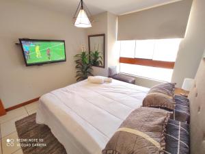 ein Schlafzimmer mit einem großen Bett und einem Fernseher an der Wand in der Unterkunft DEPARTAMENTO con BALCÓN DE 3 HABITACIONES CERCA DE TODO in Chiclayo