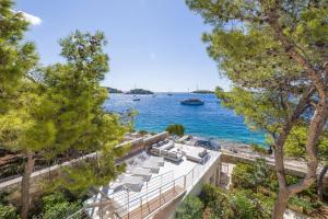 a view of the water from a building with lounge chairs at Magnificent Seafront Villa 10 Bedrooms Pakleni View Villa Private Infinity Pool & Amazing Sea Views Hvar Town in Hvar