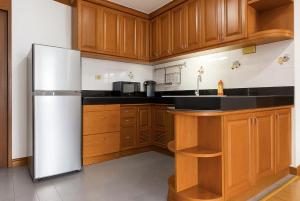 Una cocina con gabinetes de madera y refrigerador. en Comfy King Room with Private Beach and Ocean View, en Na Jomtien