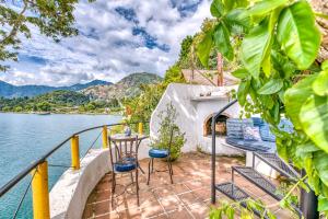 a balcony with chairs and a table and water at Casa Paloma - Lakefront - Waterfalls - Gardens in San Marcos La Laguna